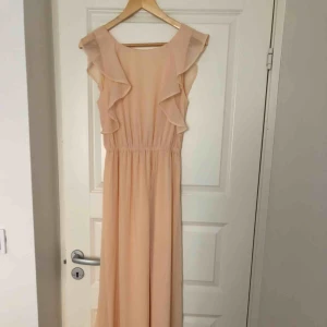  - Långklänning i drömmig och skir puder/laxrosa, chiffong, öppen i ryggen. Perfekt skick, använd 1 ggn. Känns mer som strl 36/38, perfekt längd på mig (är 175) Som gjord för bal, studenten, bröllop etc 