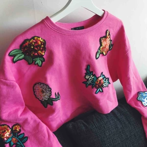  - Oversized starkt rosa sweater med paljettblommor utspridda i härliga färger. Använd en gång. Kortare passform alltså cropped.  