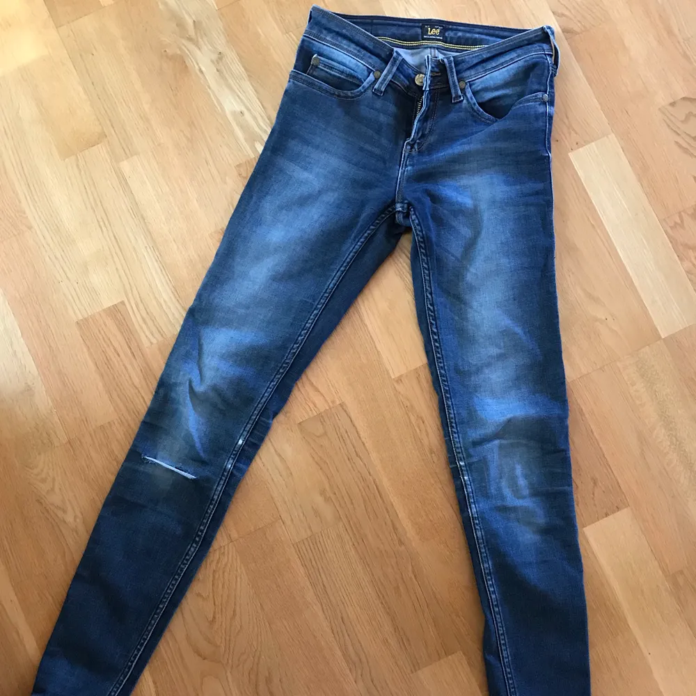 Ett par mörkblå jeans från Lee som använts en del och har någon slitning där bak och något hål på ena knäet. Men de är fortfarande i väldigt fint skick!. Jeans & Byxor.