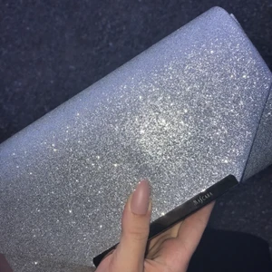 Glittrig Väska  - Endast använd en gång. Finns en silvrig kedja som går att ta av och på. 