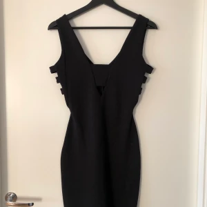 River Island - svart bodycon klänning - Tight svart bodycon klänning. V-ringad fram och bak. 3 straps på sidorna. Stl 34 i EUR, 8 i UK. Använd 2 gånger.