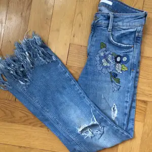 Jeans med blå blommor vid fickorna och fransiga där nere. Från Zara i storlek 34. Bra skick!