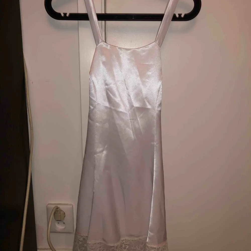 En vit siden klänning med korsning bak Har även spets nertill. Klänningar.