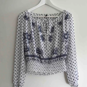  - Oanvänd blus i tunt material med lätt balkongärm. Resår vid ärmens slut och i midjan. 