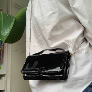  - Helt oanvänd väska från Carin Wester. Frakt ingår ej i priset. Svart lack med många fack för ex kort.