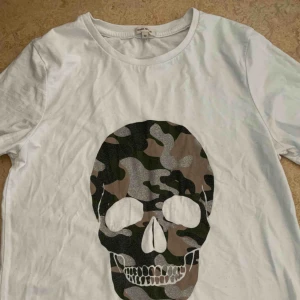  - En t-shirt från River island med en döskalle på Inte använd på ca 1 år men i lika fint skick som när jag köpte den Storlek 10 vilket motsvarar stl 36 i Sverige, den är lite oversize men inte jätte