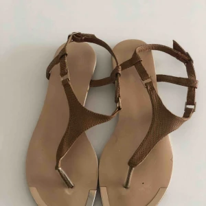  - Beige sandal med metalldetalj framtill. I fint skick. Hämtas i Malmö eller skickas mot frakt. 