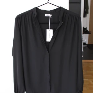 Filippa K - Alva Blouse - Svart - XS - NY! - Märke: Filippa K. Typ: Alva Blouse. Storlek: XS, passar nog även en S då den är något stor. Färg: Svart. Nypris: 1400 kr. Skick: Helt ny och oanvänd, med prislapp kvar.  Produkt info: Material: 100% polyester, Tyg: Chiffong, Skötselråd: Torktumlas ej, 30°C maskintvätt, skontvätt Produktinformation Krage: Kinakrage/ståkrage, Förslutning: Knapp, Transparens: Delvis, Mönster: Enfärgat. Fastpris: 749 kr inkl frakt, självklart spårbart. 