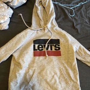 Grå Levis hoodie, storlek M - Grå levishoodie med blå, röd och svart logga på framsidan, som ny