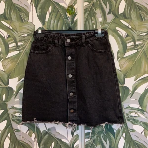 NA-KD svart jeanskjol storlek 36 - Svart jeanskjol med knappar fram.  Den är ett år gammal och endast använd ett fåtal gånger. Längd ca. 43cm. Ordinarie pris; 300kr