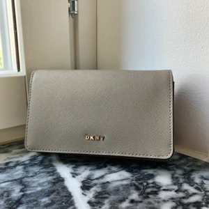 Äkta DKNY-plånbok  - DKNY-plånbok köpt på NK. Många platser för kort samt myntfack. Färgen är gråbeige. Nypris 900kr.