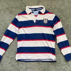 Randig Gant Piké - Blå vit röd-randig gant piké i bra skick. Storlek 13-14 ÅR