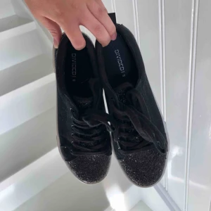  - Höstens coolaste sneakers! Superfina platåsneakers i svart canvastyg. Svart glitter på främre och bakre delen av skon. Använda några få gånger men bra skick! Kan frakta mot fraktkostnad.
