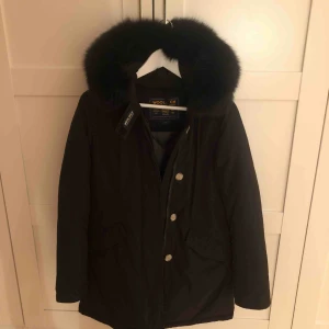  - Woolrich parkas med svart päls i storlek S. Limiterad edition, glansigt material och fantastiskt fin svart päls, använd ett fåtal gånger.