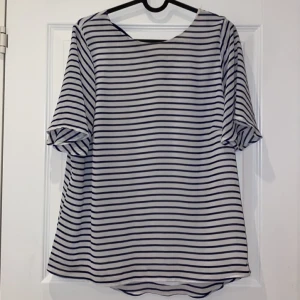 Randig blus, storlek: 42 - En randig blus med en rosett på ryggen. Storlek: 42. Aldrig använd. Frakt tillkommer.