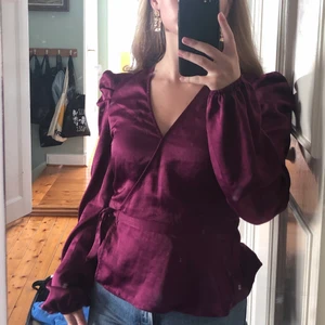 Lila omlottblus med puffärmar - Verkligen så fin lila omlottblus! Har inte kommit till användning, vilket e väldigt synd. Tyget är lite satin-liknande, glansigt och lent med lite puffärmar. Köpt för ungefär en månad sen från bikbok! Som ny, inga defekter. Köpt för 400kr. Svårt att få en bild med den rätta färgen, ändrar sig mycket i olika ljus. Säg till för fler bilder!❤️  JAG STÅR FÖR FRAKTEN