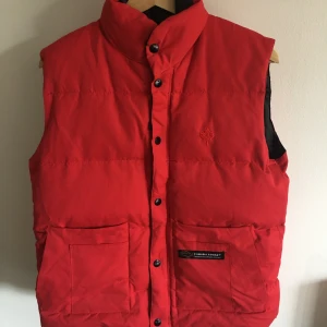 CANADA GOOSE VÄST - RÖD XS  - Snygg canada goose väst i en fin röd färg. Bra skick! Kolla gärna in mina andra annonser för mer fint! 