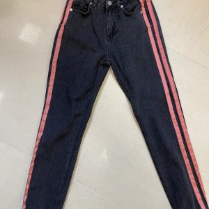 Jeans NAKD - Svart/grå jeans med snygga rosa detaljer på utsida lår, tighta med raka i modellen, storlek 32. ENDAST ANVÄNDA 2-3 gånger, passar ej mig längre.