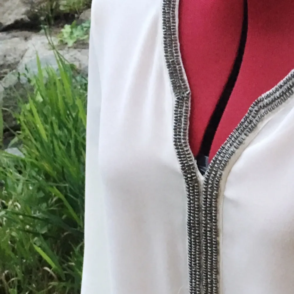 Snygg naturvit blus från Zara med granitgråa pärlor broderade kring halsen!  (Använd fåtal gånger). Blusar.