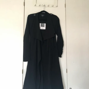 Trenchcoat - En trenchcoat från Vero Moda, oanvänd. Bortklippta axelvaddar. Köpt för 600kr. Storlek XS
