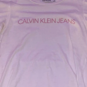 Calvin Klein T-shirt  - SUPER SKÖN vit Calvin Klein T-shirt med ljus rosa text. Helt oanväd! Storlek M 