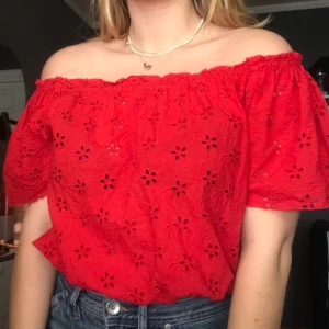Röd off shoulder topp - Röd off shoulder topp med cut outs i form av blommor. Resår längst ner så går att ha mer croppad eller dra ner. Använd 1 gång. 