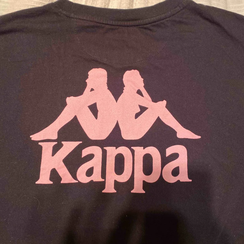 Svart Kappa T-shirt i fint skick i storlek S. Säljs pga använder aldrig. Ljus rosa tryck på vänster bröst samt rygg. T-shirts.