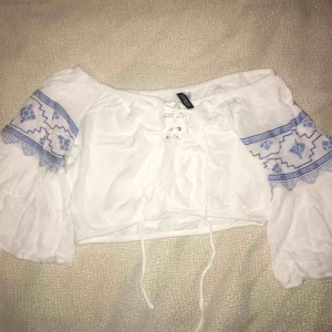  - Croppad off shoulder top från hm. Blå mönster vid armarna som e lite bredare. Priset kan diskuteras :)