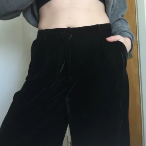  - Vida sammetsbyxor från Monki.   Svarta byxor i sammet med fickor, bältesöglor och en sydd fika i bak. Hög midja och utställda hela vägen. Aldrig använda.   Sorry för dåliga bilder, svårt att göra byxorna rättvisa på bild! 
