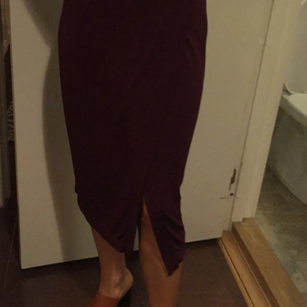 Midi-kjol i vinröd färg med slit på vänster framsida . Kjolar.