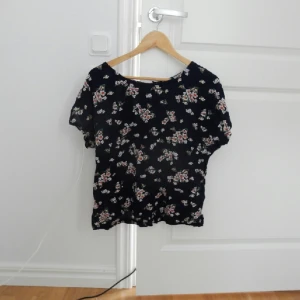  - Kortärmad mörkblå blus med blommor från Lindex. Använd men fortfarande fin. Knappar i ryggen. 