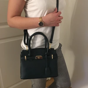  - En väska som inte kommit till användning & är stilren! Färgen är marinblå ( ser svart ut på bild) med gulddetaljer! Frakten ingår! 