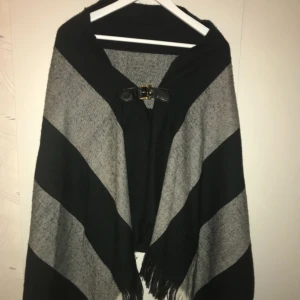  - En fin poncho med spänne fram