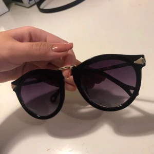  - Svarta solglasögon med guldiga detaljer. Snygga i sommar antingen på eller som en fin accessoar på huvudet. Utan styrka, säljes pga synfel 50kr + ev frakt