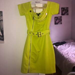 En gulgrön klänning med skärp i midjan! Aldrig använd! Strl 34. Frakt får man står för själv!