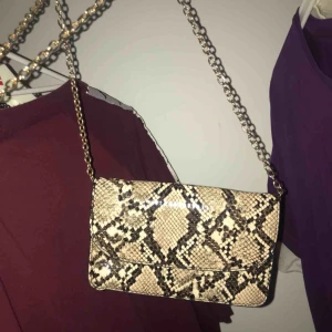 💼  - Crossbody/axelväska i ormmönster, kommer med ett matchande skärp så den även kan användas som midjeväska! Kedjan går att justeras.