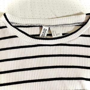 Ribbad topp i stretchig bomullstrikå, oanvänd, strl S - Långärmad tröja i ribbad stretchig  bomullstrikå. Vit med svarta ränder.  Storlek S, normal passform Helt oanvänd.  Nypris 129 kr  Säljes för 39 kr  Finns i Sundbyberg men kan lämnas på annan plats i Stockholm alternativt skickas med post 