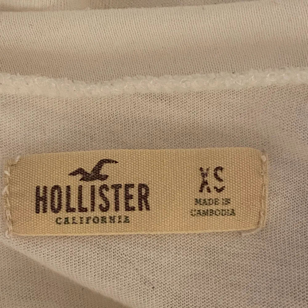 En vit hollister t-shirt med tryck på bröstet, använd några gånger och är i storlek XS. Ner stoppad på både bild ett och två. . Toppar.