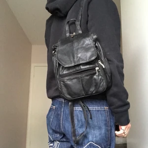 Svart vintage ryggsäck  - Säljer denna vintage ryggsäcken. Axelremmarna kan sättas ihop med hjälp av en dragkedja som man kan se på tredje bilden. Väskan har många bra fack, skriv flr fler bilder. Frakt är 66 kr eller mötas upp i sthlm <3