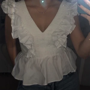 H&M blus strl 36  - En super fin vit sommarblus med volanger från H&M! Aldrig använd då den aldrig kommit till användning. Nypris ca 299 kr.