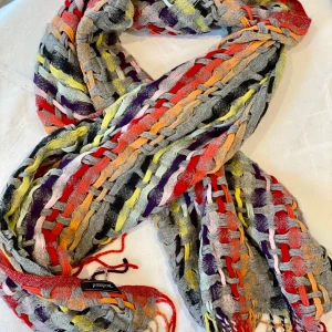 Halsduk multifärgad - En exklusiv halsduk från tyska modemärket PASSPORT Fashion. Stickad i ull, aldrig använd! Underbara färger. Längd 170 cm, bredd 50 cm. Kan mötas upp i Sollentuna eller skicka med post (frakt tillkommer). Ord. pris ca 995:-