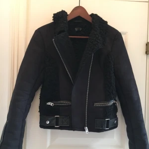  - Snygg och varm bikerjacka från topshop strl 36. Den är mörkblå/svart i mocka material och svart ull på insidan som håller en varm. Skinndetaljer. Oanvänd, endast hängt i garderoben.  Hämtas på Kungsholmen 