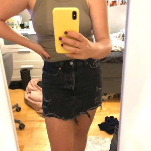 Svart Levis kjol - En svart Levis kjol med slitningar. Otroligt skön och väldigt bra skick, inte sönder någonstans. Storlek 25 (S) men är ganska stretchig.  Du knäpper med knappar inte dragkedja (gylf) frakt kan tillkomma. Köpt för 500kr säljer för 170kr