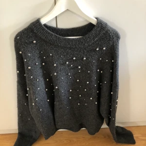 Fin stickad tröja med pärlor - Stickad tröja med pärlor på. Storlek s men passar större och mindre storlekar. Mörk grå färg.  Köparen står för frakten.