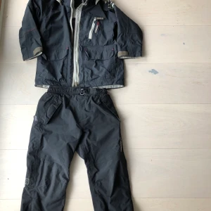 Skaljacka och överdragsbyxor - Blå jacka välanvänd men hel, svart byxa litet hål baksida knäceck