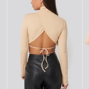 Beige body med öppen rygg - Sååå fin beige body med öppen rygg och hög hals! Den är verkligen inte alls mycket använd, kanske max 5 gånger. Köpt från NA-KD för 350 kr. Kan skicka egna bilder om så önskas🥰 Köparen står för frakten💜