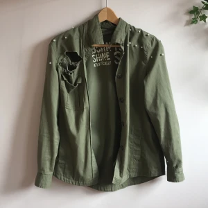 Grön höstlig jacka - Grön höst jacka med vita pärlor och hål på axlarna. Köpte Secondhand från början, aldrig använd sen dess! Funkar för många storlekar. Jag bär vanligtvis XS.