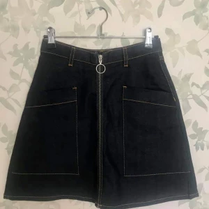 90-tals jeanskjol från Monki med dragkedja  - En minikjol från Monki i mörkt denim. 90-tals/clueless anda. Storlek 34. Aldrig använd men har hunnit ta bort prislappen. Nypris är 250 kr. Säljer den för 150 kr inkl frakt. Kan antingen mötas upp i Stockholm eller frakta🌸