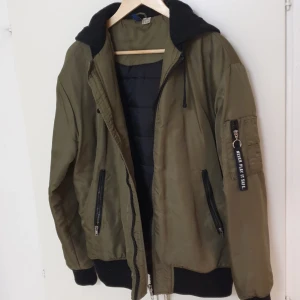 Mörkgrön bomberjacka - Fodrad bomberjacka med text på luvan. Från HM Divided.