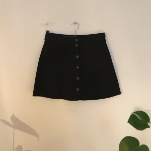  - Svart jeanskjol med knappar.